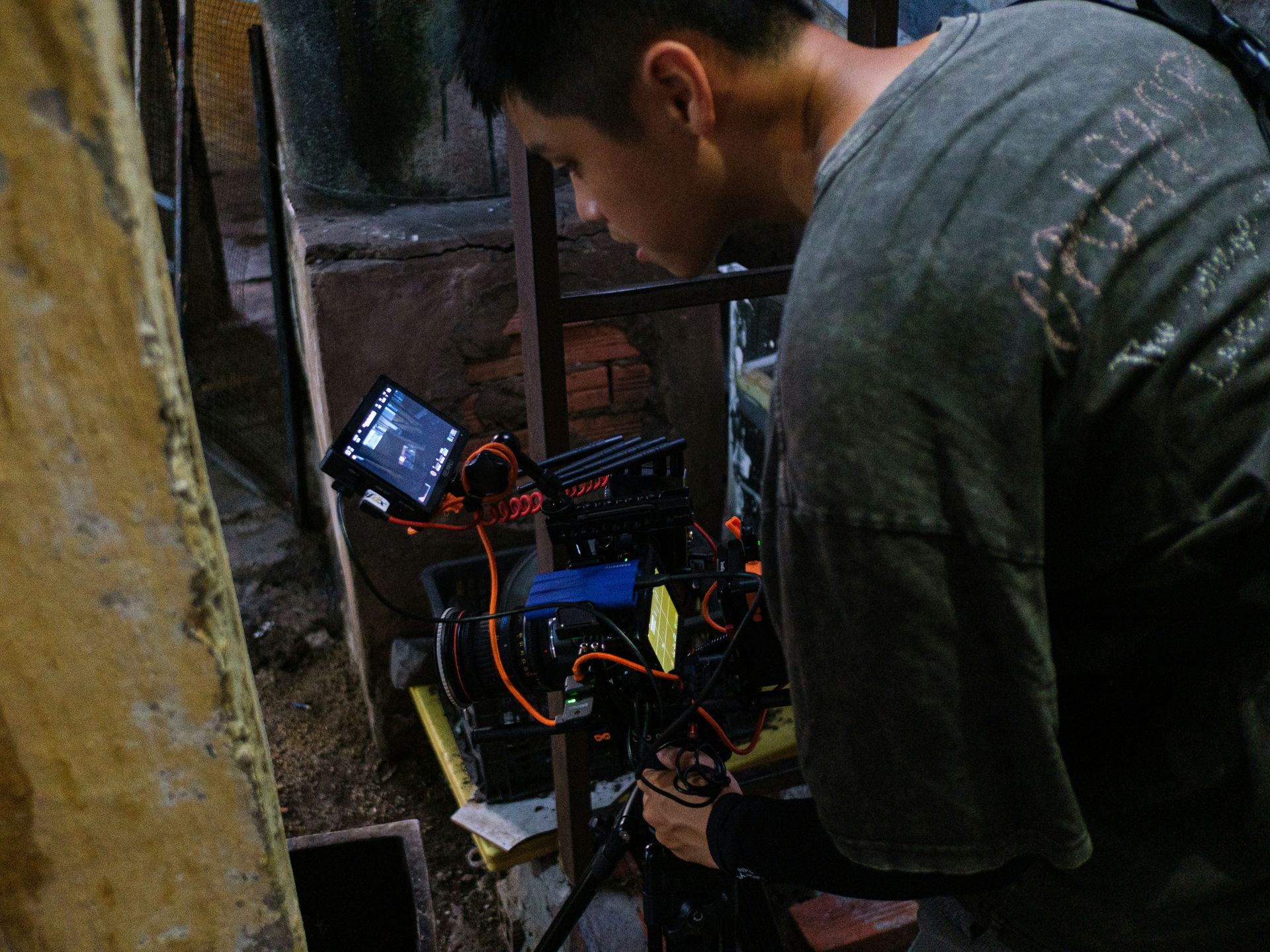 Man adjusting a professional video camera setup indoors.