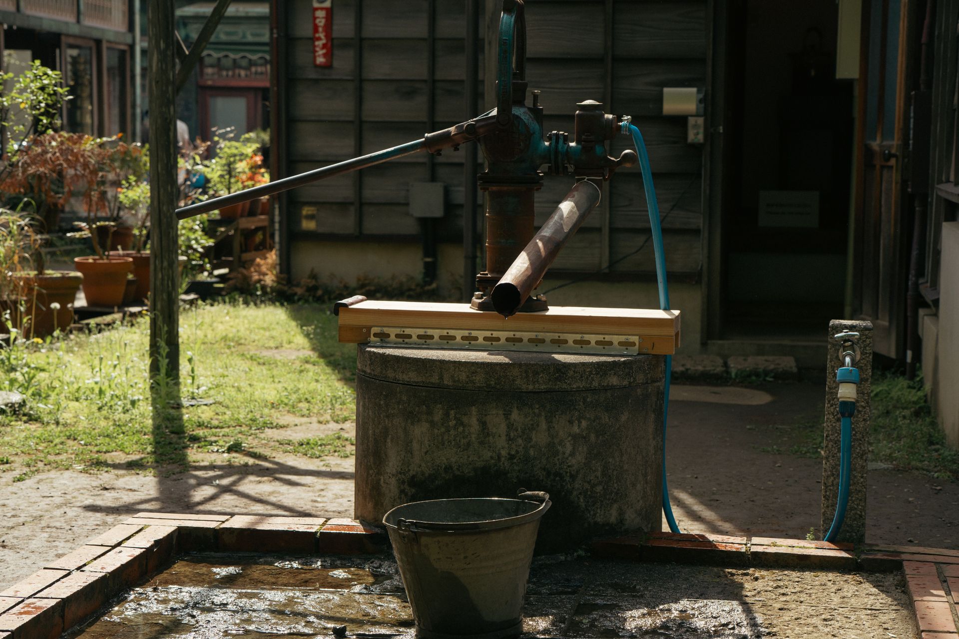 A classic water pump in a serene Tokyo garden setting, capturing rustic charm.